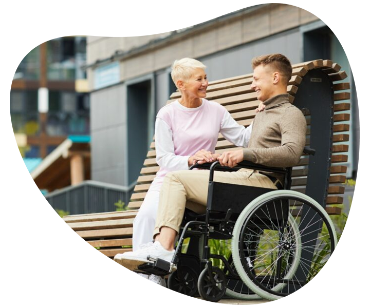 An older woman and a man in a wheelchair having a discussion, symbolising disability support services.