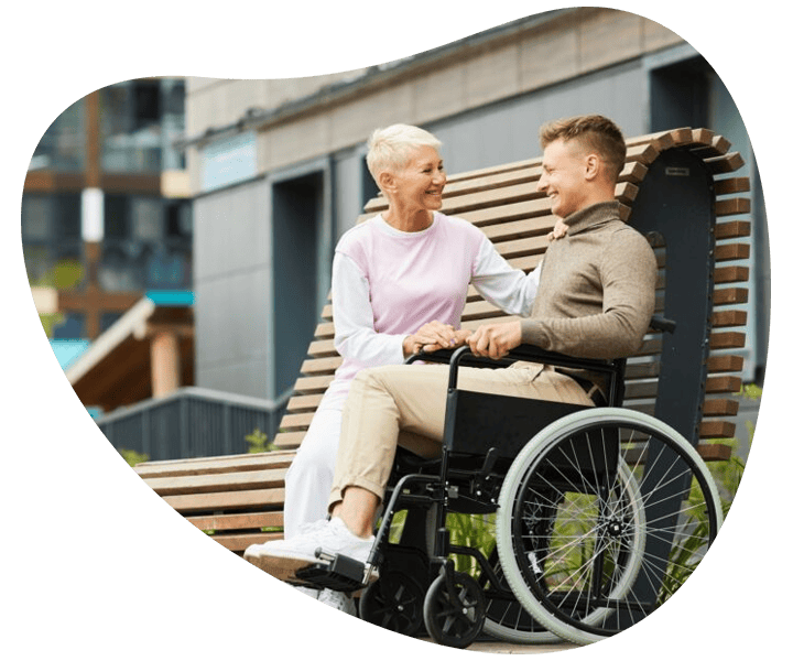An older woman and a man in a wheelchair having a discussion, symbolising disability support services.