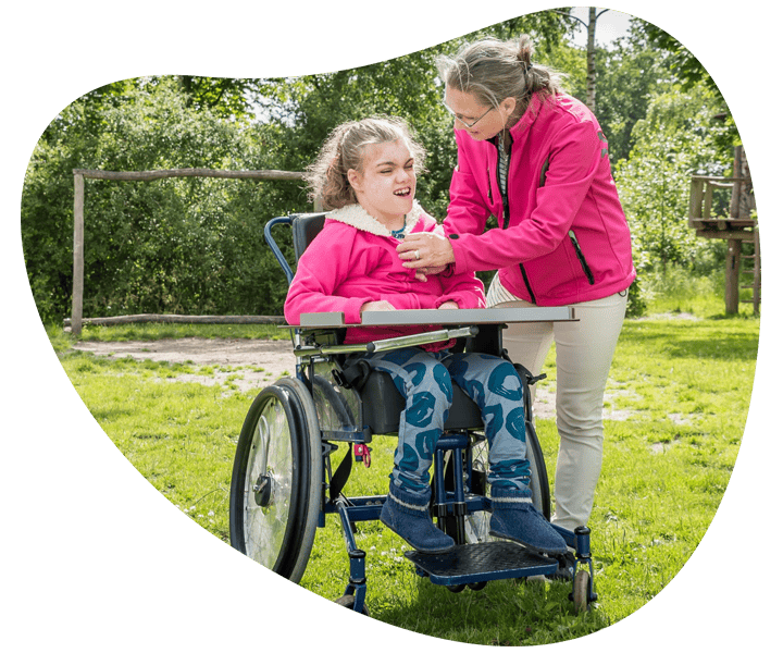 A child in wheelchair receiving NDIS assist-personal activities from a woman