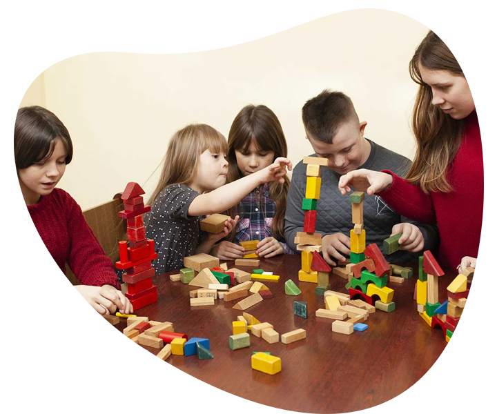Children playing with wooden blocks at a table, engaging in NDIS community participation.
